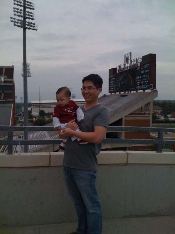 Ba muốn chụp hình ở sân banh của trường. Con thì dòm mấy cái lá gió thổi bay dưới đất