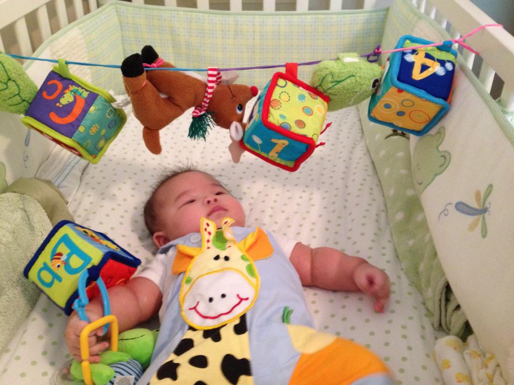 Có đồ chơi treo trong nôi em thích lắm.