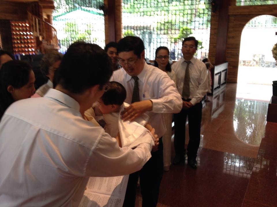 Bác Hoàng là cha đỡ đầu mặc áo choàng cho em.