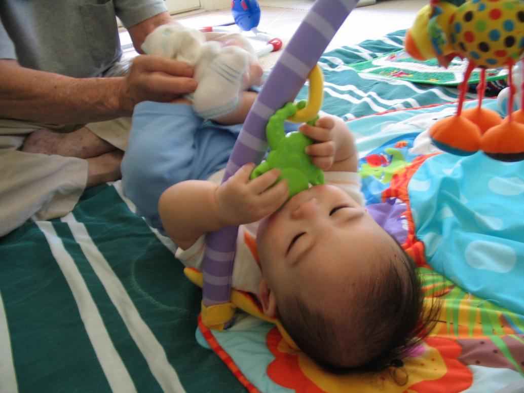 Ông Nội thì cầm chân cho con...gặm đồ chơi...