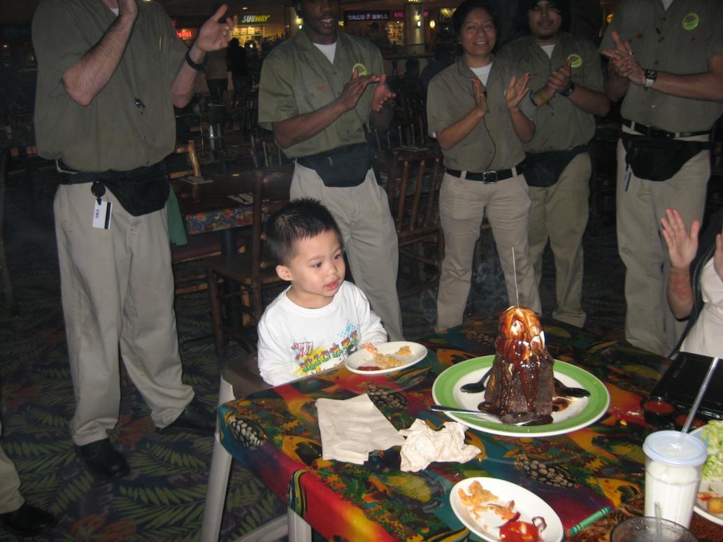 Bây giờ mình ăn sinh nhật tạm ở nhà hàng. Có mọi người hát và bánh kem núi lửa.